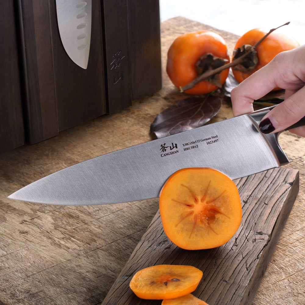 
                  
                    Load image into Gallery viewer, Person using a chef&amp;#39;s knife to cut persimmons on a wooden cutting board.
                  
                